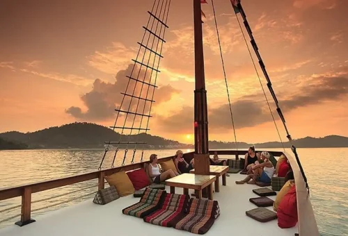 Guests relaxing on a wooden boat deck at sunset in Phuket