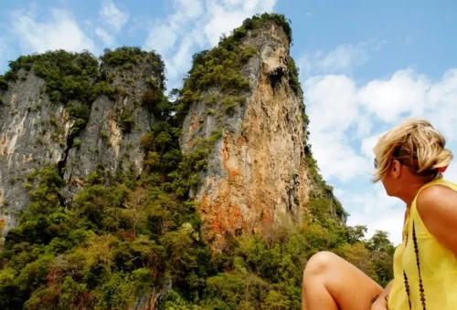 Woman admiring giant limestone cliffs during a Phuket Phang Nga day cruise.