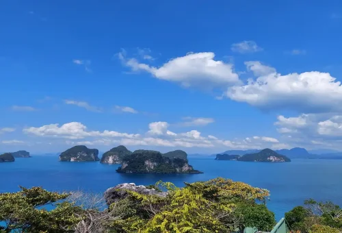 Scenic panoramic view of limestone islands in Phang Nga Bay under a clear blue sky.