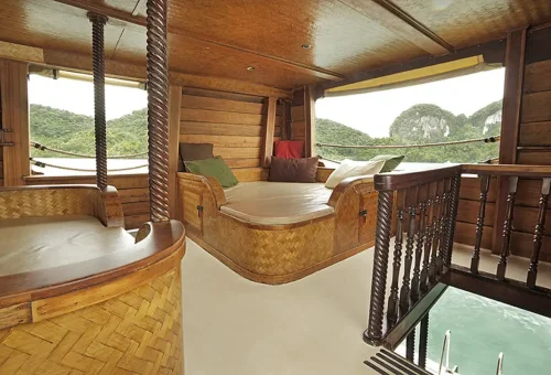Wooden interior lounge with soft cushions aboard MY Phuket Champagne day cruise boat.