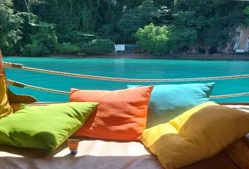 Bright cushions on deck overlooking turquoise waters at Phang Nga Bay with Phuket Travel Store cruise.