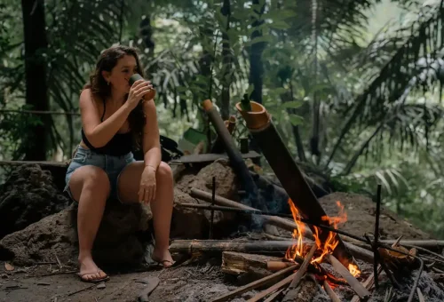 Woman enjoying coffee brewed in bamboo cup during Khao Sok bamboo rafting tour.