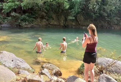 Travelers swimming in natural jungle river pool at Khao Sok.