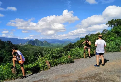 Tourists at scenic Khao Sok viewpoint overlooking limestone mountains.
