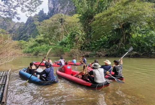 Small group canoeing along Sok River with limestone cliffs in background.