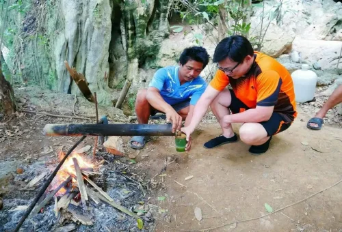 Tourist enjoying traditional bamboo-brewed coffee in Khao Sok jungle.