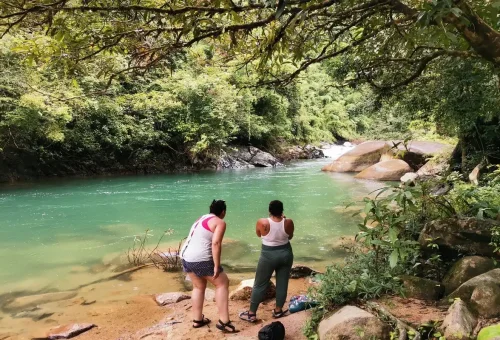 Travelers standing by emerald-green river in Khao Sok jungle.