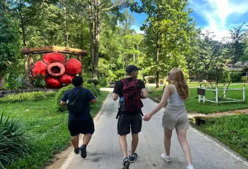 Tourists at Khao Sok National Park entrance with giant Rafflesia flower statue.