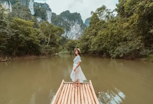 Woman standing on bamboo raft with stunning Khao Sok cliffs