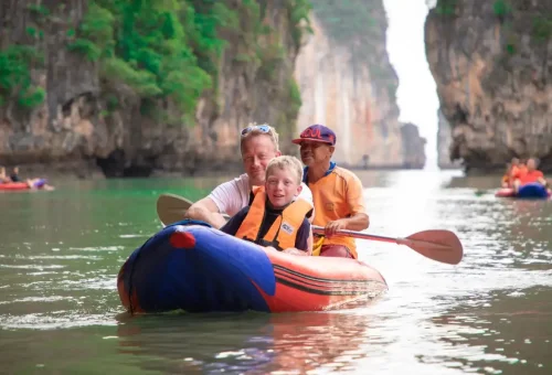 Family with guide enjoying kayaking through limestone cliffs on Phang Nga Bay Sunset Serenity Cruise by Phuket Travel Store.