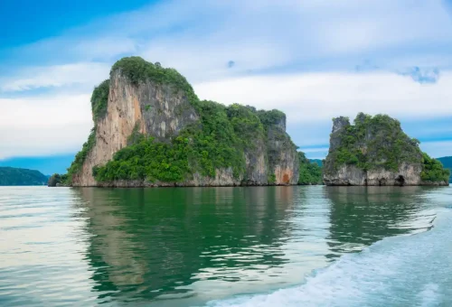 Scenic limestone islands reflecting on calm emerald waters of Phang Nga Bay during Sunset Serenity Cruise with Phuket Travel Store.