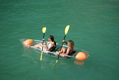 Two women paddling transparent kayak over emerald waters during Phang Nga Bay Sunset Serenity Cruise with Phuket Travel Store.