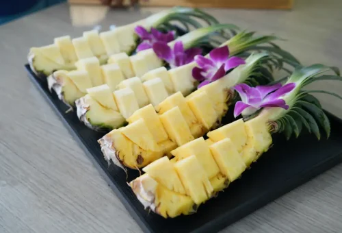 Fresh pineapple decorated with orchids served onboard Phang Nga Bay Sunset Serenity Cruise with Phuket Travel Store.