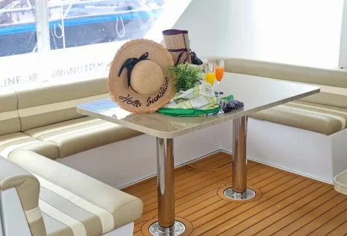 Cozy lounge seating with drinks and summer hat inside luxury yacht on Phang Nga Bay Sunset Serenity Cruise with Phuket Travel Store.