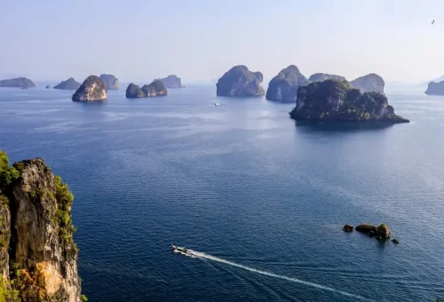 Longtail boat cruising among limestone islands near Hong Island, Krabi.