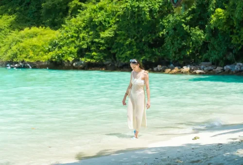 Woman walking along clear turquoise water at Bamboo Island in Krabi
