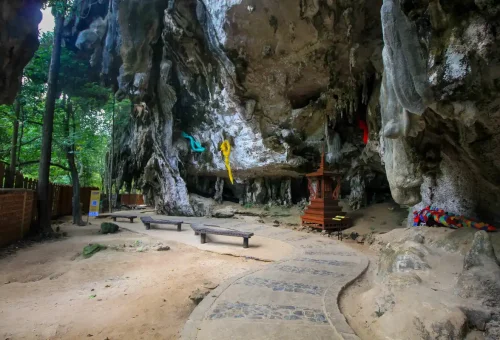Sacred cave shrine at Pranang baech in Krabi with colorful offerings.