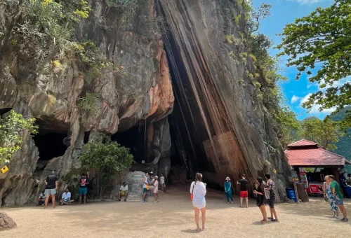Tourists exploring limestone cave entrance at Phang Nga Bay