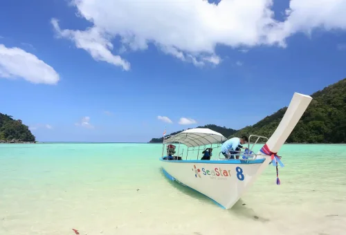 Longboat anchored in crystal-clear water at Surin Islands Thailand.