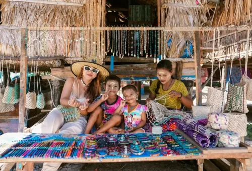 Traveler with Moken family crafting handmade jewelry in Surin Islands village.