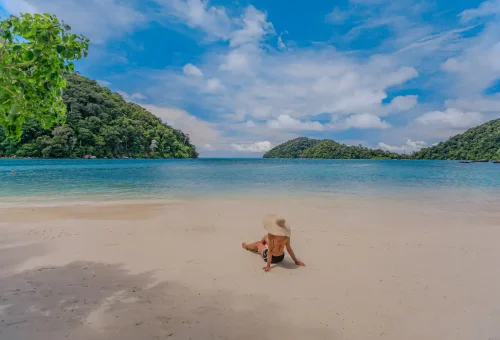 Woman with sun hat sitting under tree at Surin Islands Thailand