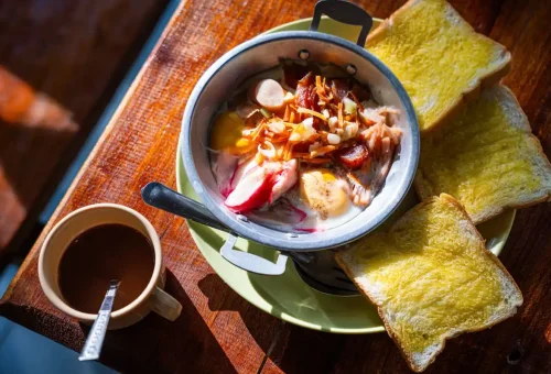 Traditional Thai breakfast with pan-fried eggs, sausage, and toast served with coffee