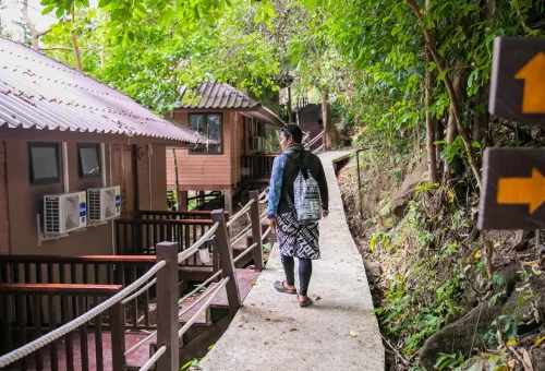 Traveler walking to wooden bungalow accommodation in forest at Surin Islands Thailand