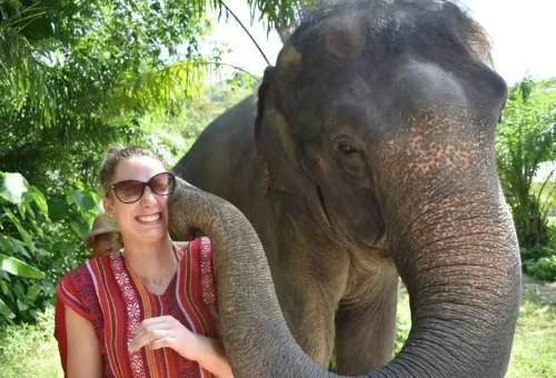 Elephant gently touching a smiling tourist’s face with its trunk at Phuket Elephant Care Park.