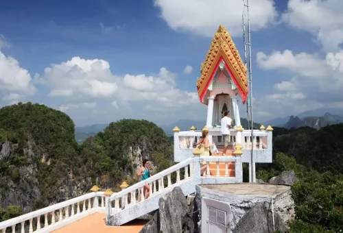 Visitors climbing stairs to mountaintop shrine overlooking lush valleys of Krabi.
