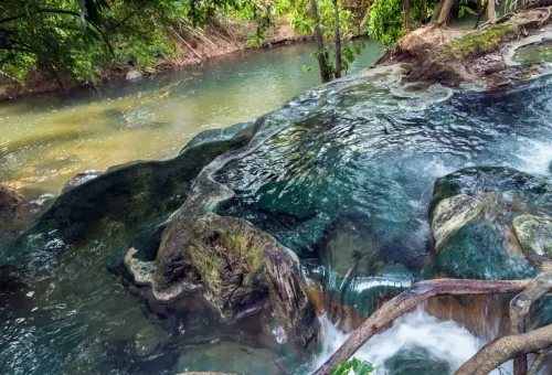 Steaming hot spring cascading over smooth rocks in Krabi’s jungle.