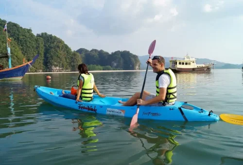 Couple kayaking in calm sea near traditional boats at Ao Thalane Krabi