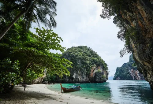 Longtail boat anchored at the beach of Koh Hong Island under limestone cliffs – Krabi day tour.