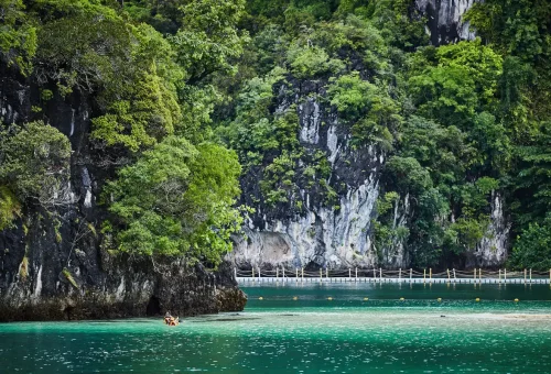 Kayakers exploring emerald waters and limestone caves at Ao Thalane, Krabi, Thailand.
