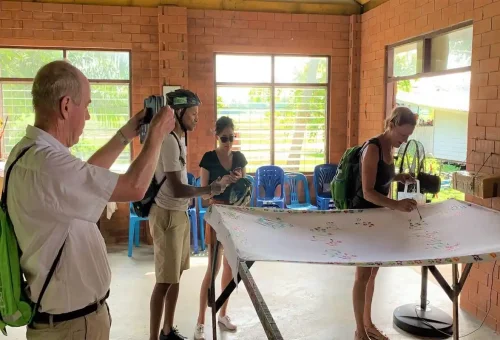 Travelers painting batik cloth inside local workshop in Krabi