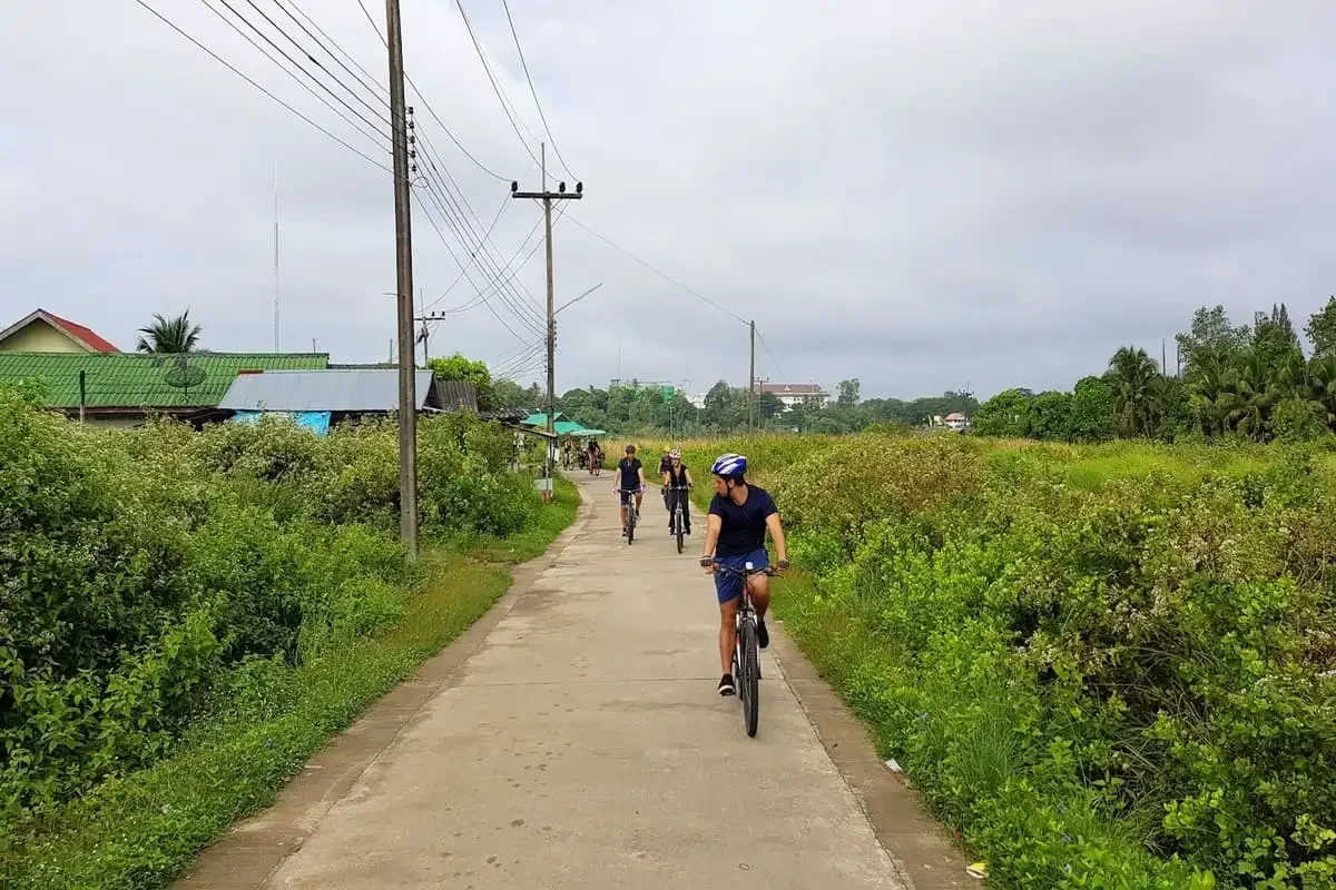 Cyclists riding through countryside lanes of Krabi