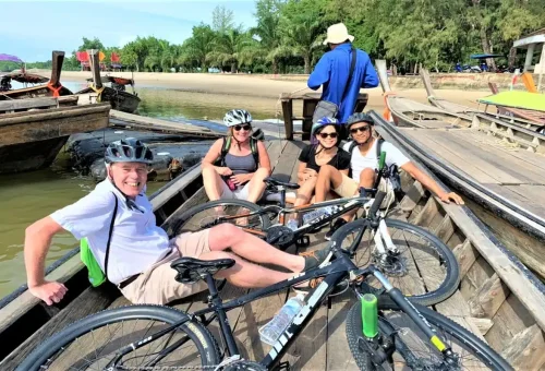 Tourists with bicycles on wooden longtail boat at Krabi pier