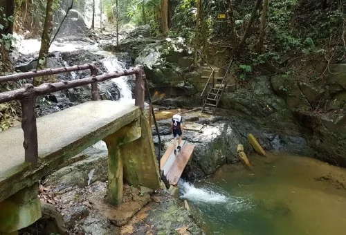 Traveler crossing a bridge near the cascading Huay Tho Waterfall during the Krabi cycling trip.