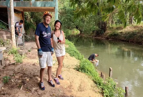Couple posing during Krabi Huay Tho Waterfall cycling tour with helmets and scenic backdrop.