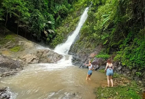 Visitors enjoying a refreshing swim at the Huay Tho Waterfall pool after a cycling tour.