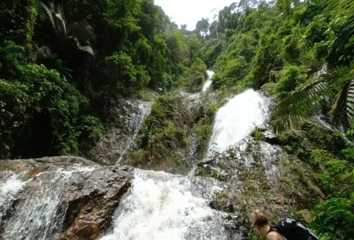 View of cascading Huay Tho Waterfall surrounded by tropical rainforest.