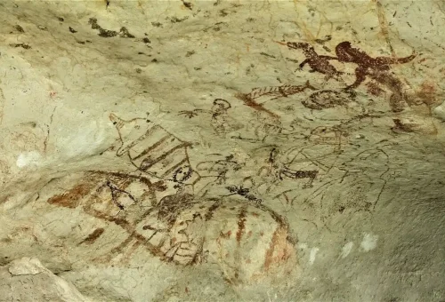 Ancient rock art showing human and animal figures inside a limestone cave in Phang Nga Bay.