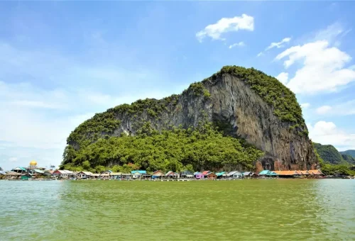 Scenic view of Koh Panyee village at the base of a limestone cliff with colorful rooftops.