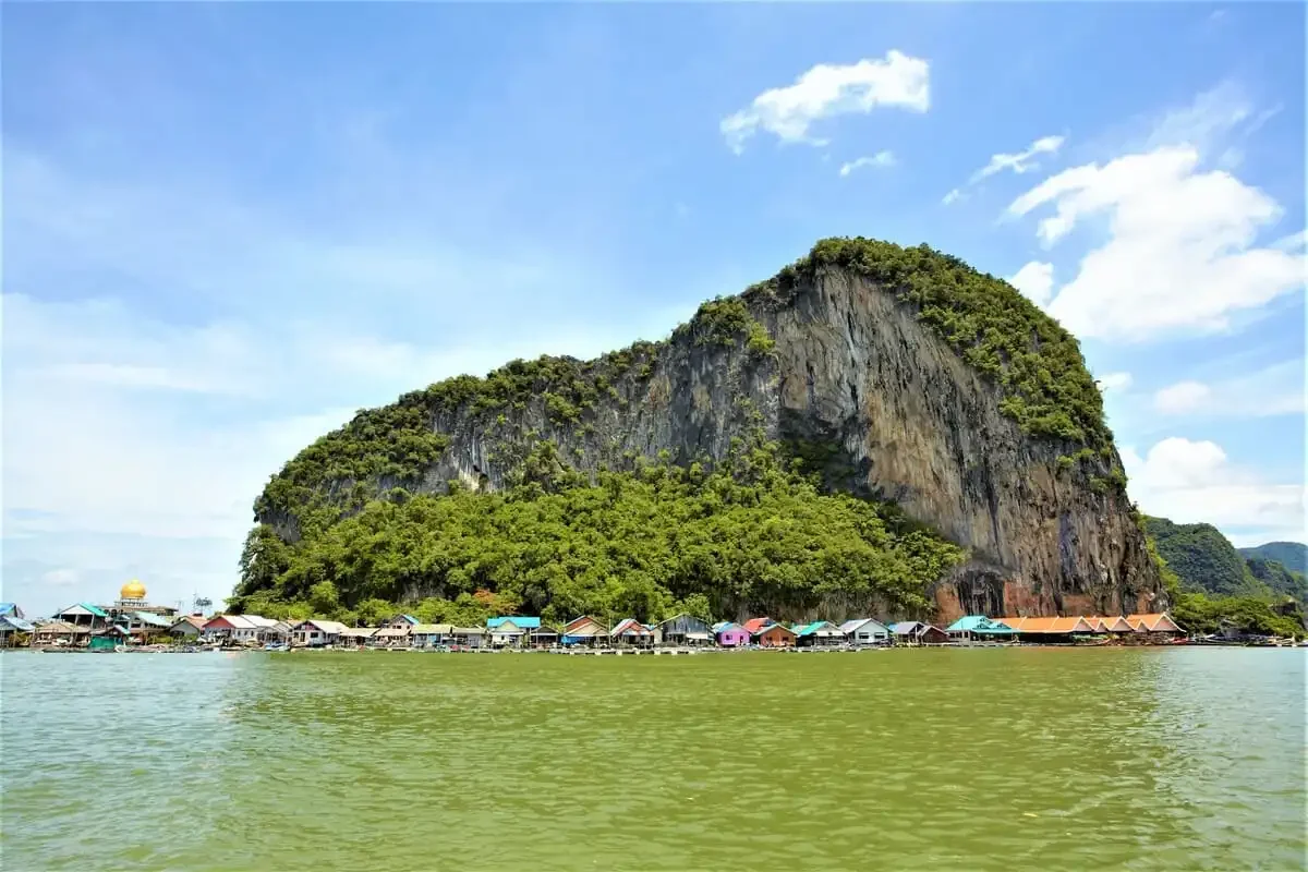 Scenic view of Koh Panyee village at the base of a limestone cliff with colorful rooftops.