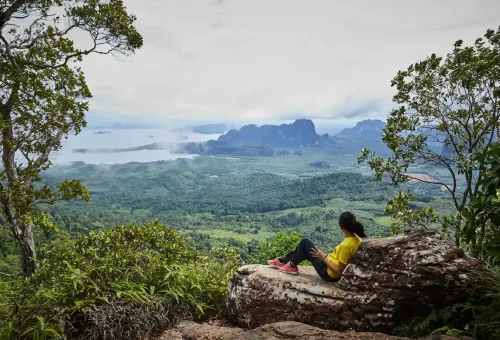 Relaxing on a rock viewpoint at Dragon Crest Mountain with misty morning view.