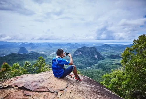 Tourist taking photo of scenic mountain view from the Dragon Crest peak in Krabi.
