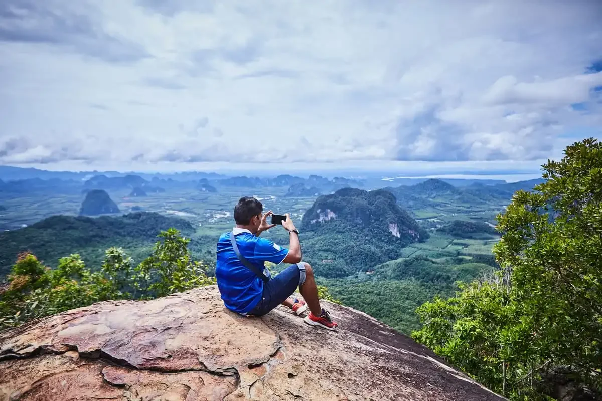 Tourist taking photo of scenic mountain view from the Dragon Crest peak in Krabi.