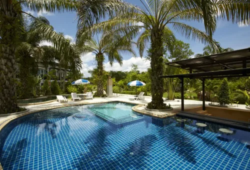 Clear blue swimming pool with sunbeds and palm trees at Krabi resort.