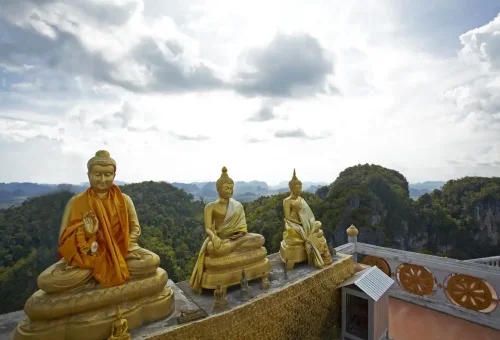 Golden Buddha statues overlooking mountains at Tiger Cave Temple, Krabi.