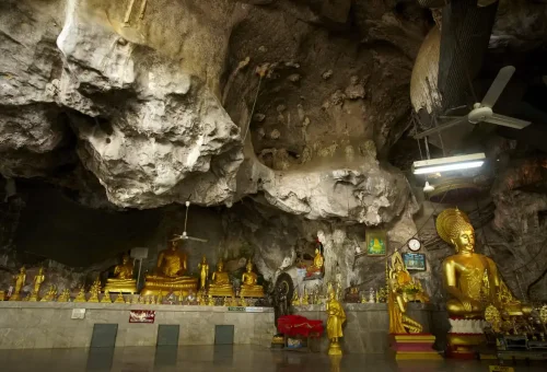 Natural cave interior with Buddha statues and rock formations at Wat Tham Suea.