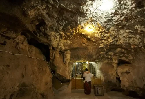 Cave shrine inside Tiger Cave Temple where visitors pray before Buddha statue.